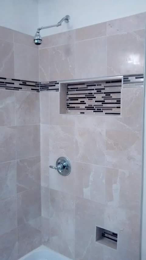 Tiled shower wall with a mosaic accent band and built-in niche