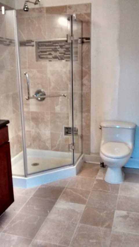 Bathroom with a tiled corner shower, glass door and mosaic accent band