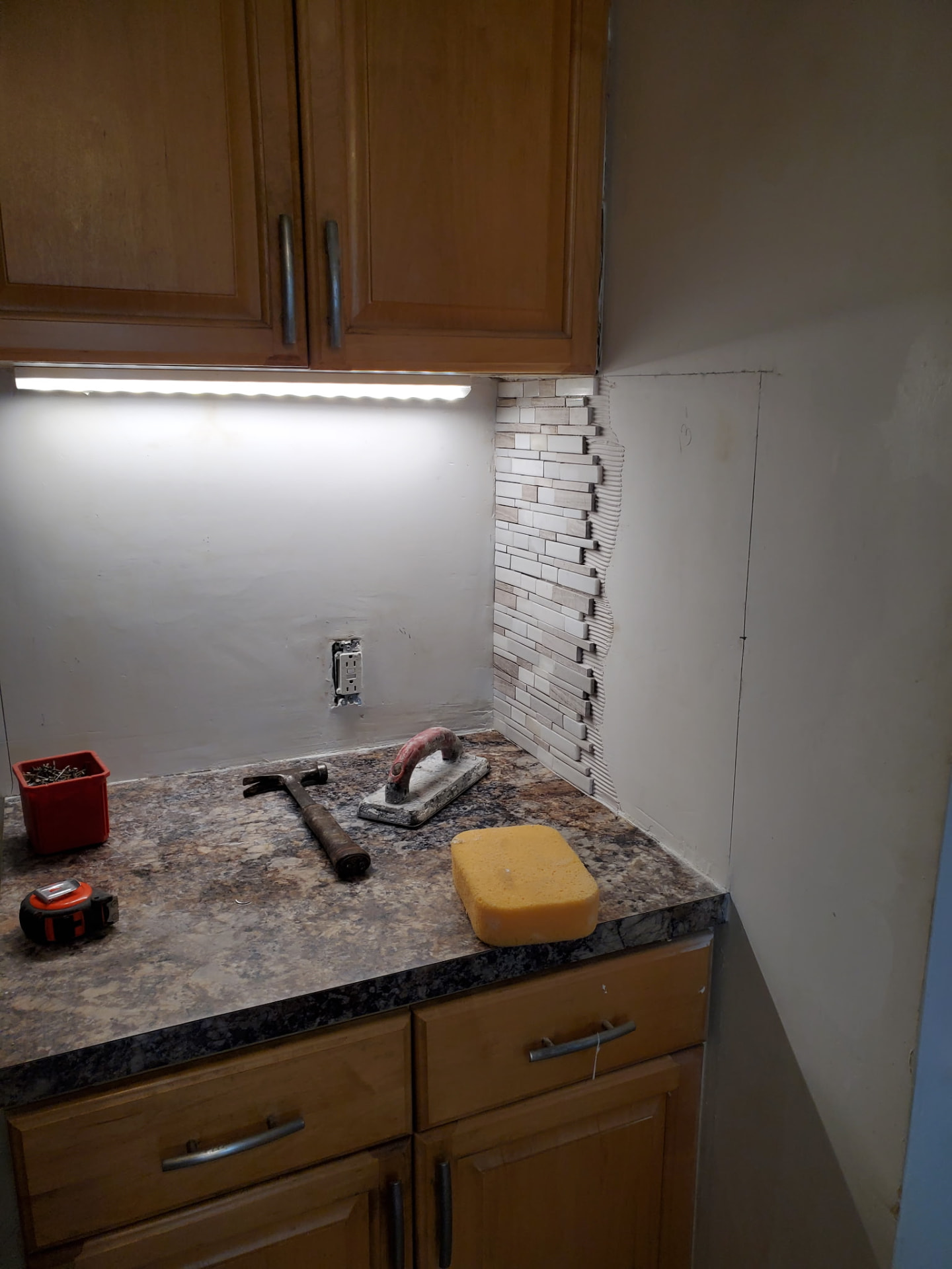 Kitchen counter with a new mosaic tile backsplash and under-cabinet lighting